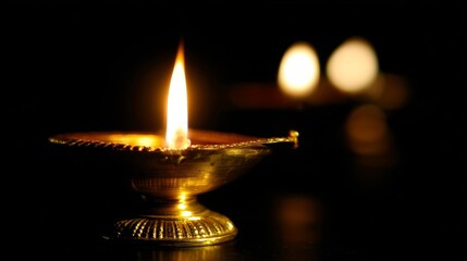 A golden traditional Indian diya glowing brightly in darkness,