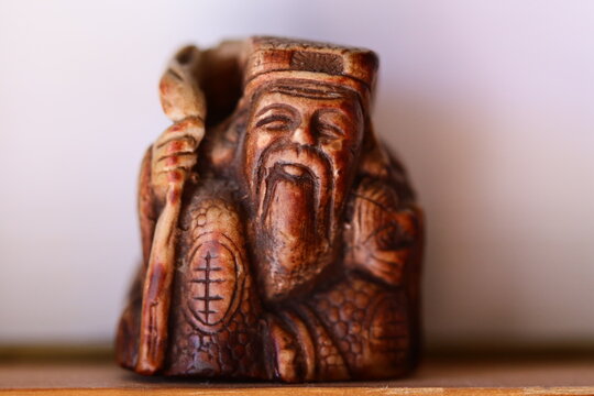 A figurine of an elderly gentleman holding a wooden staff, potentially for ceremonial or mystical purposes