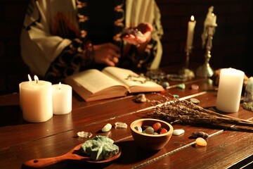 Woman doing ritual with healing stones at wooden table, closeup