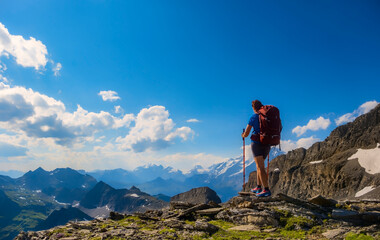 A lone hiker pauses on a rocky peak, gazing at the breathtaking mountainous terrain below. Sporty woman hiking in Switzerland alps. Heathy lifestyle, sport, beauty in nature. Grindelwald valley, Swizz