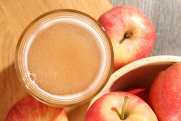 Delicious cider in glass and apples on wooden table, flat lay