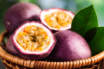 Fresh passion fruits in wicker basket on table outdoors, closeup