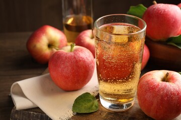 Delicious cider in glass, apples and leaves on wooden table, closeup