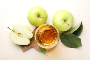 Fresh cider in glass and apples on beige table, flat lay