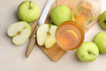 Fresh cider in glass, bottle, apples and knife on beige table, flat lay