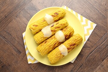 Tasty grilled corncobs with sauce on wooden table, top view