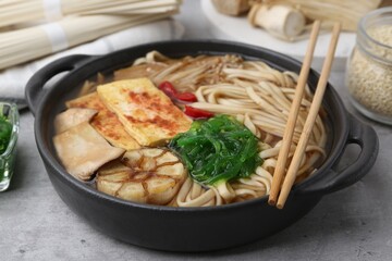 Tasty ramen with enoki and king oyster (eryngii) mushrooms on light grey table, closeup