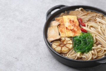Tasty ramen with enoki and king oyster (eryngii) mushrooms on light grey table, closeup. Space for text