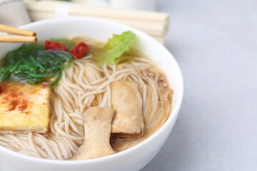 Tasty ramen with enoki and king oyster (eryngii) mushrooms on white table