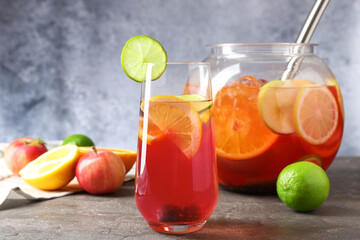 Punch and fresh fruits on grey table, closeup. Refreshing drink