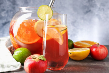 Punch and fresh fruits on grey table, closeup. Refreshing drink