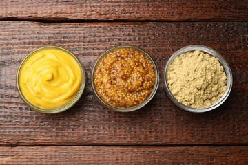 Different types of mustard on wooden table, flat lay