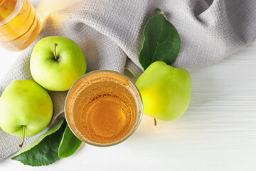 Fresh cider in glass and apples on white wooden table, flat lay