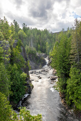 The Mississagi River flows gracefully through lush forests at Aubrey Falls, offering a breathtaking glimpse of Ontario's natural beauty.