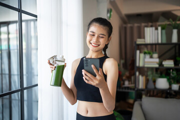 Fitness asian woman drinking organic green smoothie fruit detox for diet after workout exercise...