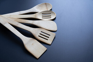 Eco-friendly bamboo kitchen utensils set isolated on black background. Wooden spoons and spatulas for cooking, serving, and healthy lifestyle. Sustainable natural design for culinary and household use