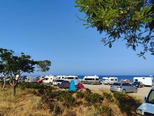 Image of camping caravans and tents on a sandy grassy campground on a beach sea coastline with blue sky photography hd quality wallpaper perfect for campaigns sunny summer day 