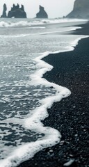 Foamy waves on a dark volcanic beach, basalt columns in the distance