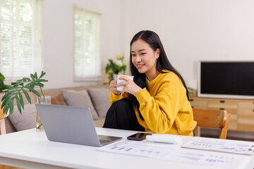 Portrait of a business asian woman is work on laptop while cup of coffee at home, business finance analysis concept
