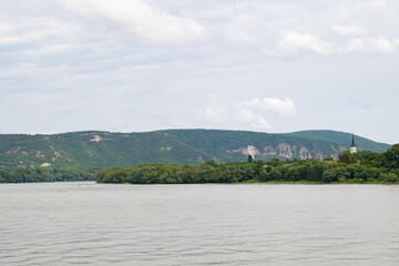 The wide waters of the Danube River and green hills. A peaceful and tranquil river view for nature lovers.