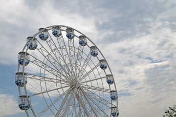 Fototapeta premium A Ferris wheel, the symbol of an amusement park, under a cloudy sky.