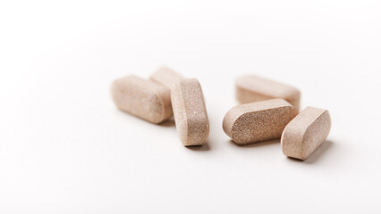 Lion’s mane mushrooms tablets that have beneficial effects on the body, especially the brain, heart, and intestines. Bright paper background. Soft focus. Close up. Copy space.	