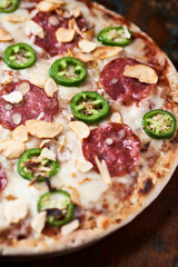 Pizza with salami, mozzarella cheese and jalapeno pepper. Wooden background. Soft focus. Copy space.	