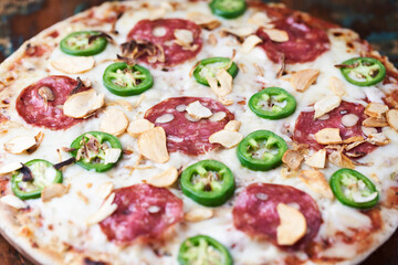 Pizza with salami, mozzarella cheese and jalapeno pepper. Wooden background. Soft focus. Copy space.	