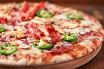 Pizza with salami, mozzarella cheese and jalapeno pepper. Wooden background. Soft focus. Copy space.	