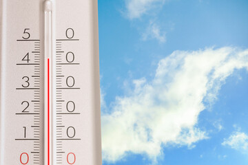 High temperature on thermometer against blue sky on sunny day. Summer weather