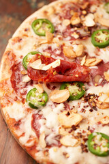 Pizza with salami, mozzarella cheese and jalapeno pepper. Wooden background. Soft focus. Copy space.	