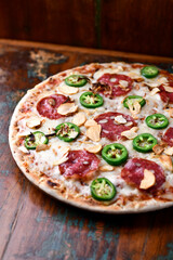 Pizza with salami, mozzarella cheese and jalapeno pepper. Wooden background. Soft focus. Copy space.	