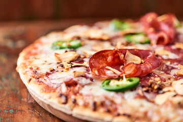Pizza with salami, mozzarella cheese and jalapeno pepper. Wooden background. Soft focus. Copy space.	