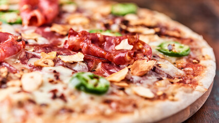 Pizza with salami, mozzarella cheese and jalapeno pepper. Wooden background. Soft focus.	