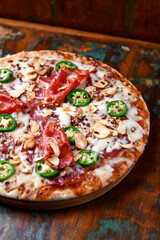 Pizza with salami, mozzarella cheese and jalapeno pepper. Wooden background. Soft focus.	