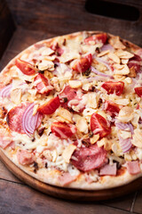 Pizza with ham, salami, cherry tomatoes and mozzarella cheese. Rustic wooden background. Soft focus. Close up.	