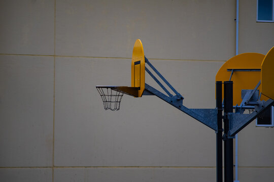Yellow Basketball Hoop with Metal Chain Net Against Wall