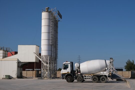White concrete mixers standing by a modern concrete plant.	