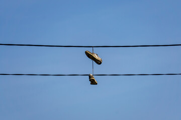 Obraz premium Shoes hanging on power lines against clear sky