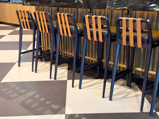 Row of tall wooden bar stools with leather seats at counter in cafe. Representation of hospitality, dining, and leisure lifestyle through modern design, tourism and culture.