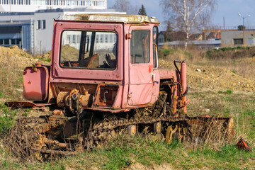 Obraz premium Old rusty crawler bulldozer abandoned in a field, damaged and incomplete, with visible corrosion and missing mechanical parts.