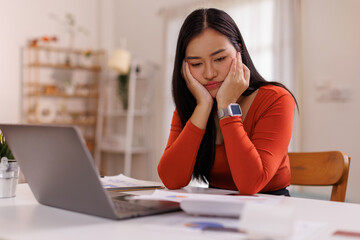 People, accounting, finances, family budget and financial issues concept. asian woman calculating domestic expenses, sitting at dining table in front of open laptop computer