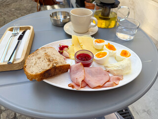 A breakfast plate with ham, cheese, eggs, bread, and jam served with tea. Nutrition, lifestyle, and dining culture illustrate morning meal, tradition, and balanced food choices.