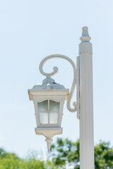 White Lamppost with Decorative Arm Against Blue Sky