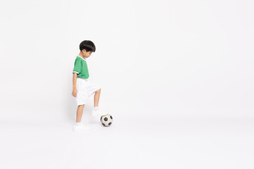 Happy Asian little boy in a green sports jersey playing football isolated on white background
