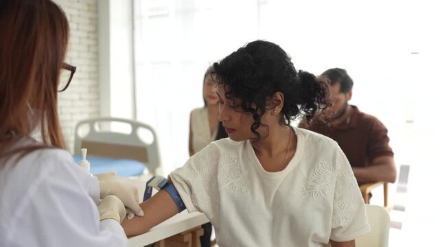 A doctor takes a blood sample from a female patient's arm in a hospital. The woman is calm during the routine health check-up, an important part of staying healthy.
