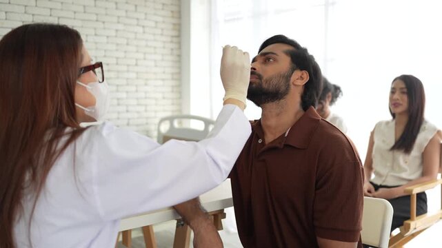 A healthcare worker takes a nasal swab from a male patient for a medical test. This sample collection is a key step for diagnosing respiratory infections like influenza or COVID-19.