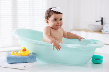 Cute little baby bathing in tub at home