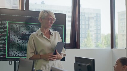 Tilt up of adorable schoolgirl asking question to smiling female teacher with tablet while sitting by workplace in front of desktop computer at lesson of programming in modern school - Powered by Adobe