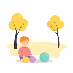 Young boy playing with colorful balls in a park during autumn  